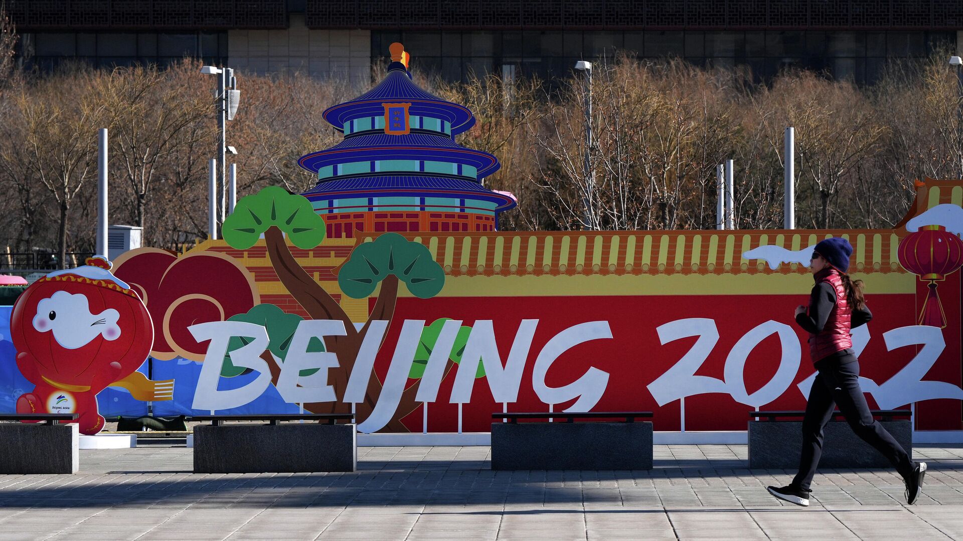 Девушка пробегает у инсталляции с символикой зимних Олимпийских игр 2022 в парке возле главного пресс-центра игр в Пекине - РИА Новости, 1920, 03.02.2022
