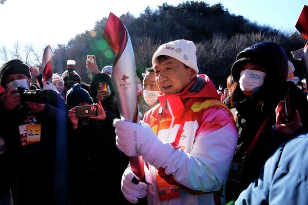 Актер Джеки Чан держит факел XXIV зимних Олимпийских игр после участия эстафете Олимпийского огня у Великой Китайской стены в Пекине, Китай