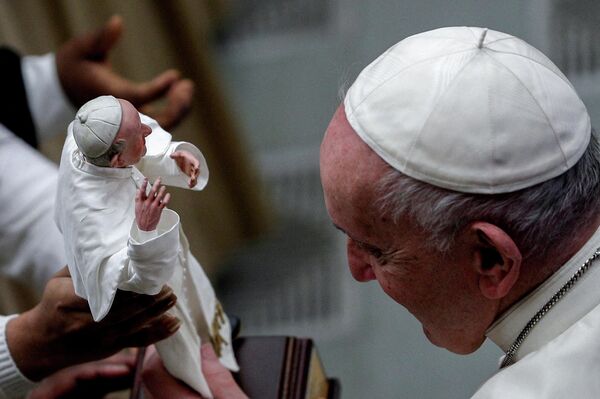 Папа Франциск смотрит на статуэтку со своим изображением в руках верующей, Ватикан