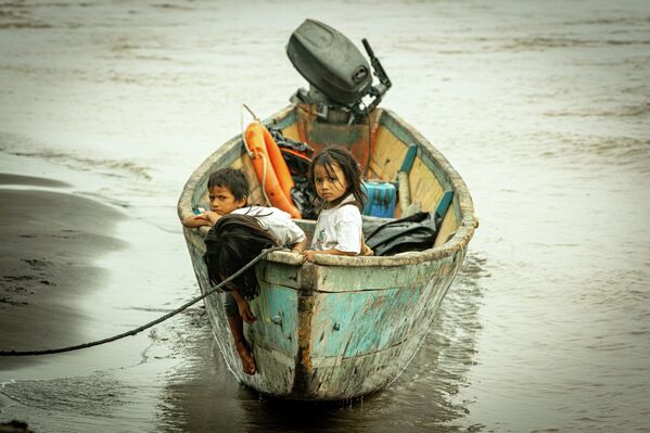 Дети сидят в лодке после разлива нефти в Пуэрто-Мадерос, провинция Сукумбиос, Эквадор