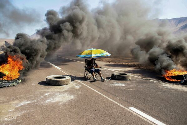 Протестующий блокирует дорогу во время демонстрации в Икике, Чили 