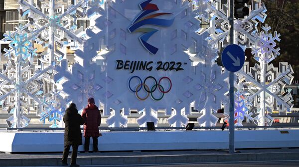 Прохожие фотографируются у стелы с символикой зимних Олимпийских игр 2022 в Пекине