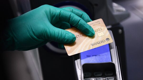 Покупатель оплачивает покупку банковской картой на кассе в продуктовом магазине в Москве
