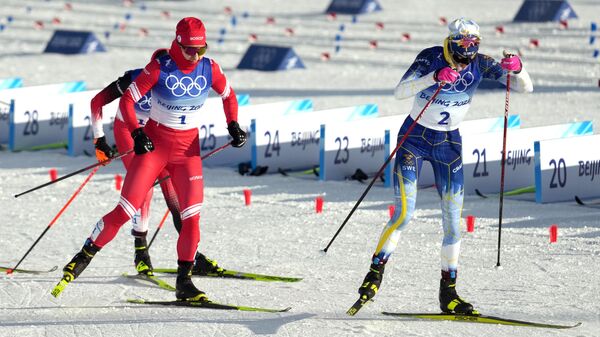 Российская спортсменка, член сборной России (команда ОКР) Наталья Непряева (слева) и Фрида Карлссон (Швеция) на дистанции 2x7,5 км скиатлона во время соревнований по лыжным гонкам среди женщин на XXIV зимних Олимпийских играх 2022.