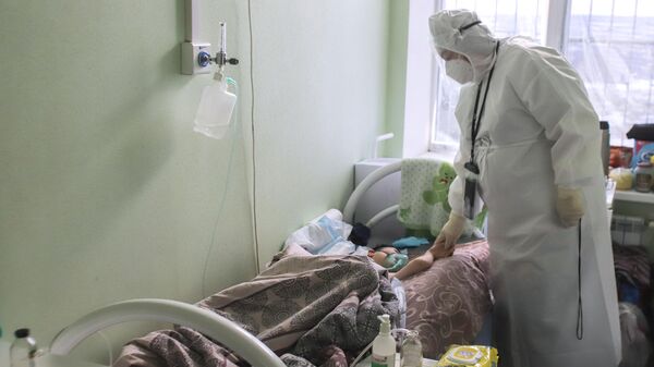 Медицинский работник у кровати ребенка в детском ковидном отделении инфекционной больницы