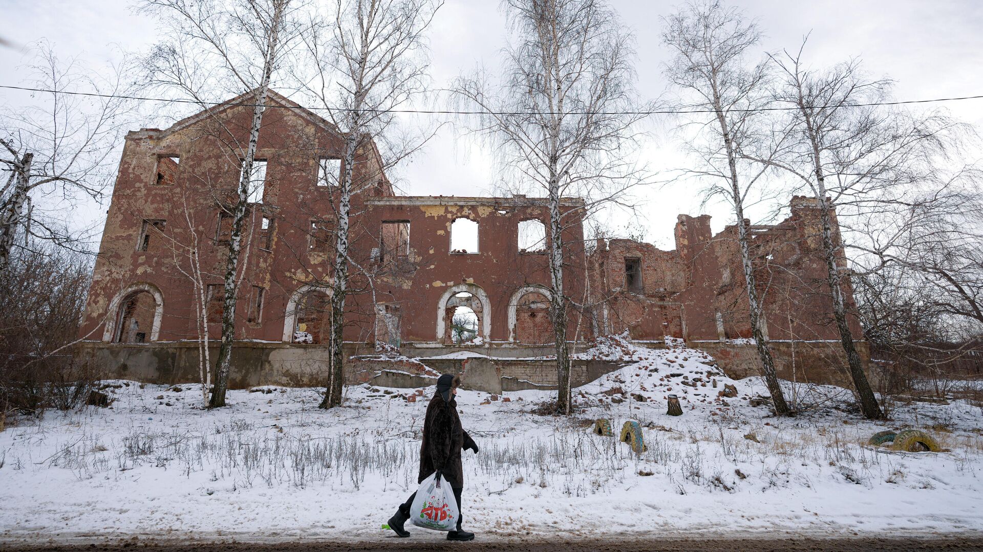 Женщина проходит мимо разрушенного здания в Славянске, Донецкая область - РИА Новости, 1920, 18.02.2024