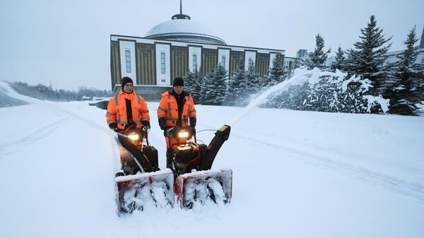 Сотрудники коммунальных служб убирают снег на Поклонной горе во время снегопада в Москве