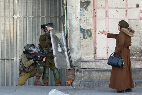 Палестинская женщина перед израильскими войсками во время акции протеста против убийства израильскими войсками трех палестинских боевиков в Хевроне 