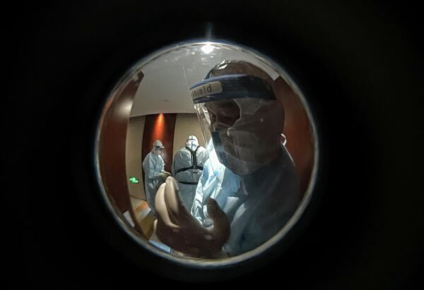 Медицинские сотрудники в защитных костюмах у номера журналиста с положительным тестом на CoVID-19 в карантинном отеле Rooy Hotels в Пекине