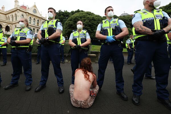 Женщина сидит перед полицией во время протеста на территории парламента в Веллингтоне, Новая Зеландия