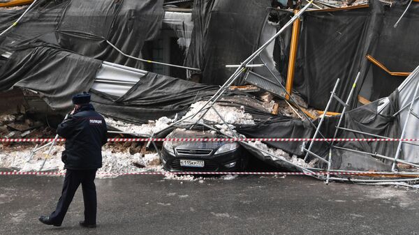 Сотрудник правоохранительных органов у обрушившихся строительных лесов возле здания в Георгиевском переулке в Москве