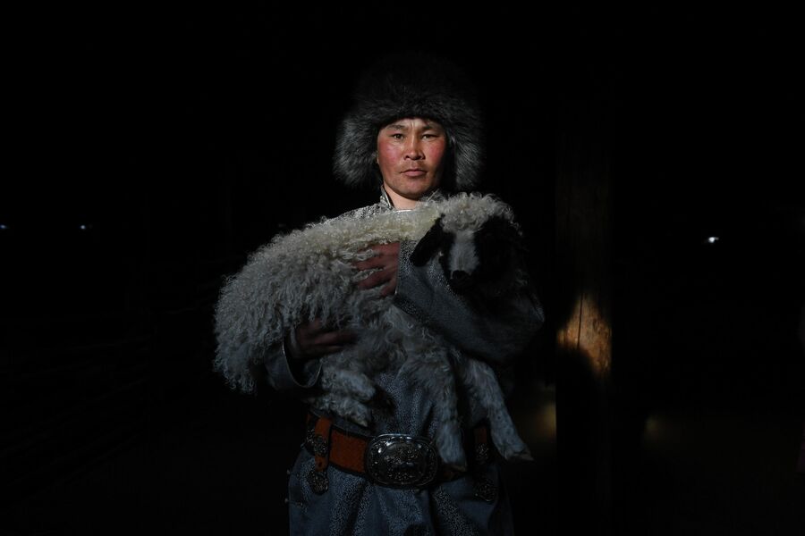 Мужчина держит на руках ягненка на чабанской стоянке в Монгун-Тайгинском кожууне Республики Тыва