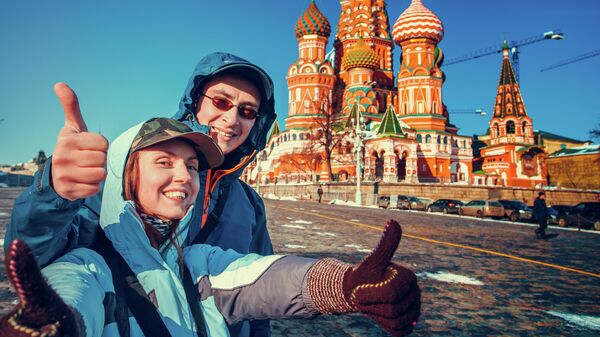 Туристы фотографируются на фоне Храма Василия Блаженного в Москве