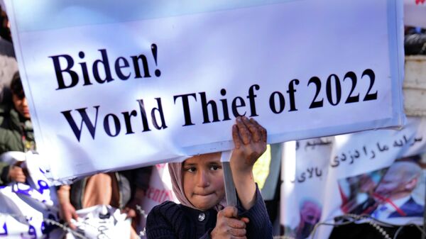 Афганская девочка в Кабуле держит плакат во время акции протеста, осуждающей решение президента США Джо Байдена