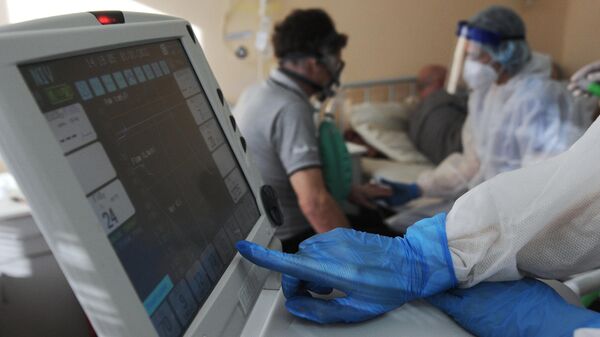Медицинский работник у кровати пациента в инфекционном отделении для больных коронавирусом