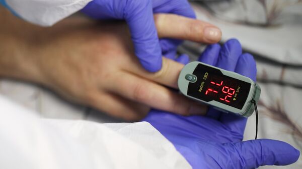 Медик использует пульсоксиметр в палате инфекционного отделения