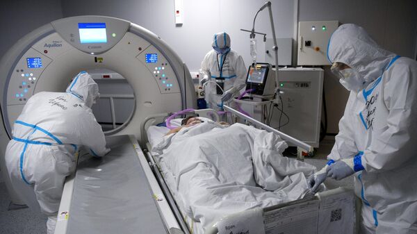 Медицинские сотрудники готовят пациента с COVID-19 к проведению компьютерной томографии