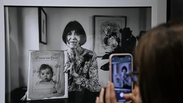 Женщина фотографирует на мобильный телефон портрет Хесси Тафт на открытии выставки The Lonka Project. Человек под номером в Еврейском музее и центре толерантности в Москве