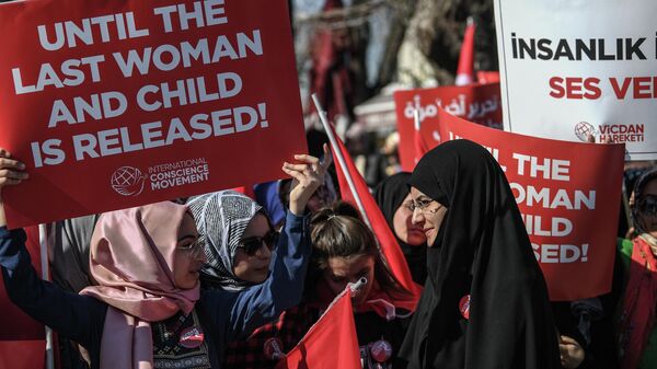 Женщины держат плакаты во время митинга против тюремного заключения женщин и детей в Сирии