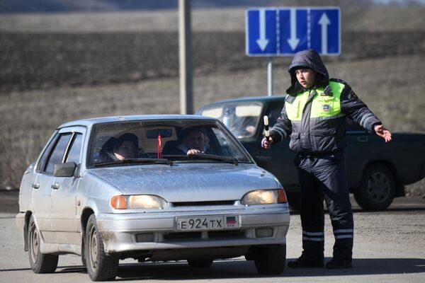 Сотрудник правоохранительных органов ДНР общается с водителем у контрольно-пропускного пункта Успенка в Донецкой области