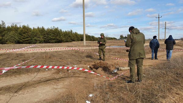 Сотрудники правоохранительных органов России на месте падения снаряда недалеко от границы с Украиной в Ростовской области