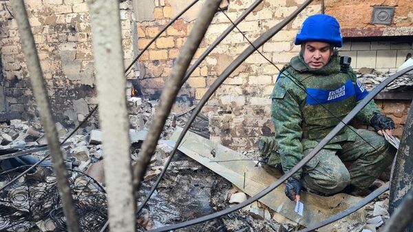 Представитель Совместного центра контроля и координации режима прекращения огня ЛНР возле дома, пострадавшего от артиллерийского удара Вооруженных сил Украины