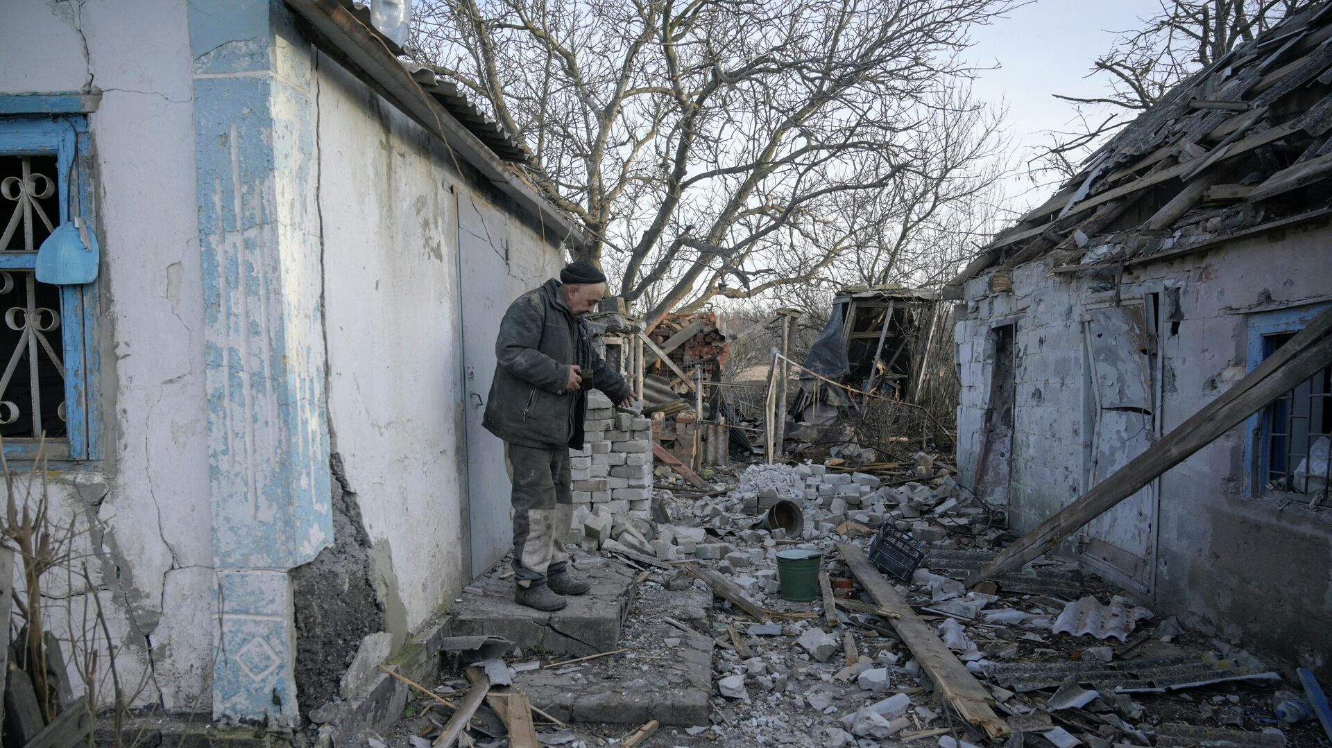 Мужчина во дворе своего дома, пострадавшего в результате обстрела в селе Тарамчук Донецкой области - РИА Новости, 1920, 21.02.2022