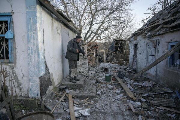 Мужчина во дворе своего дома, пострадавшего в результате обстрела в селе Тарамчук Донецкой области