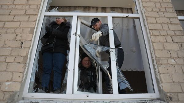 Люди демонтируют поврежденные в результате обстрела ВСУ окна