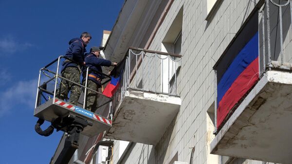 Мужчины развешивают флаги ДНР на балконах жилых домов в Донецке