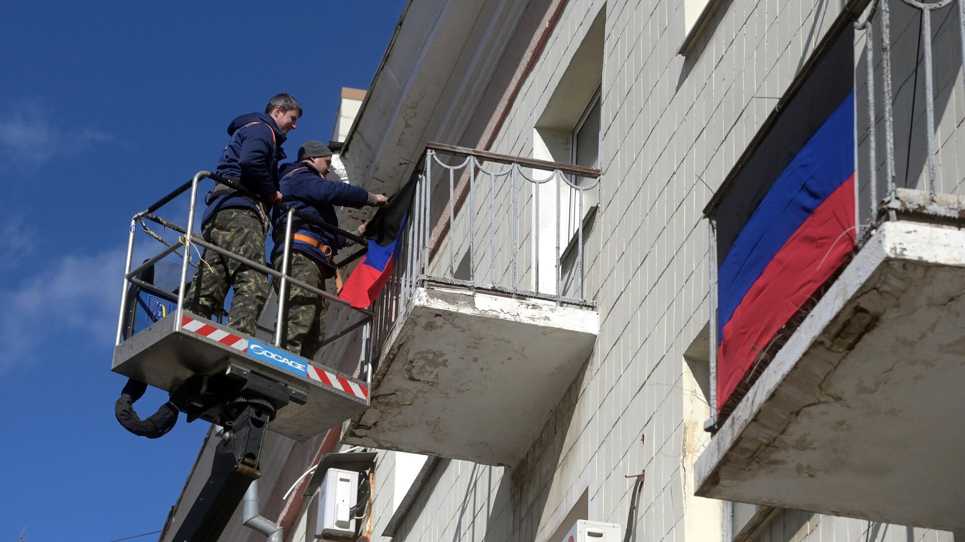 Мужчины развешивают флаги ДНР на балконах жилых домов в Донецке. - РИА Новости, 1920, 21.02.2022