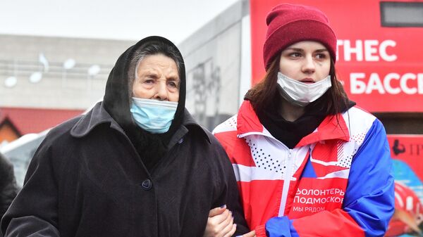Волонтер провожает женщину, прибывшую из Донбасса на железнодорожный вокзал в подмосковную Апрелевку