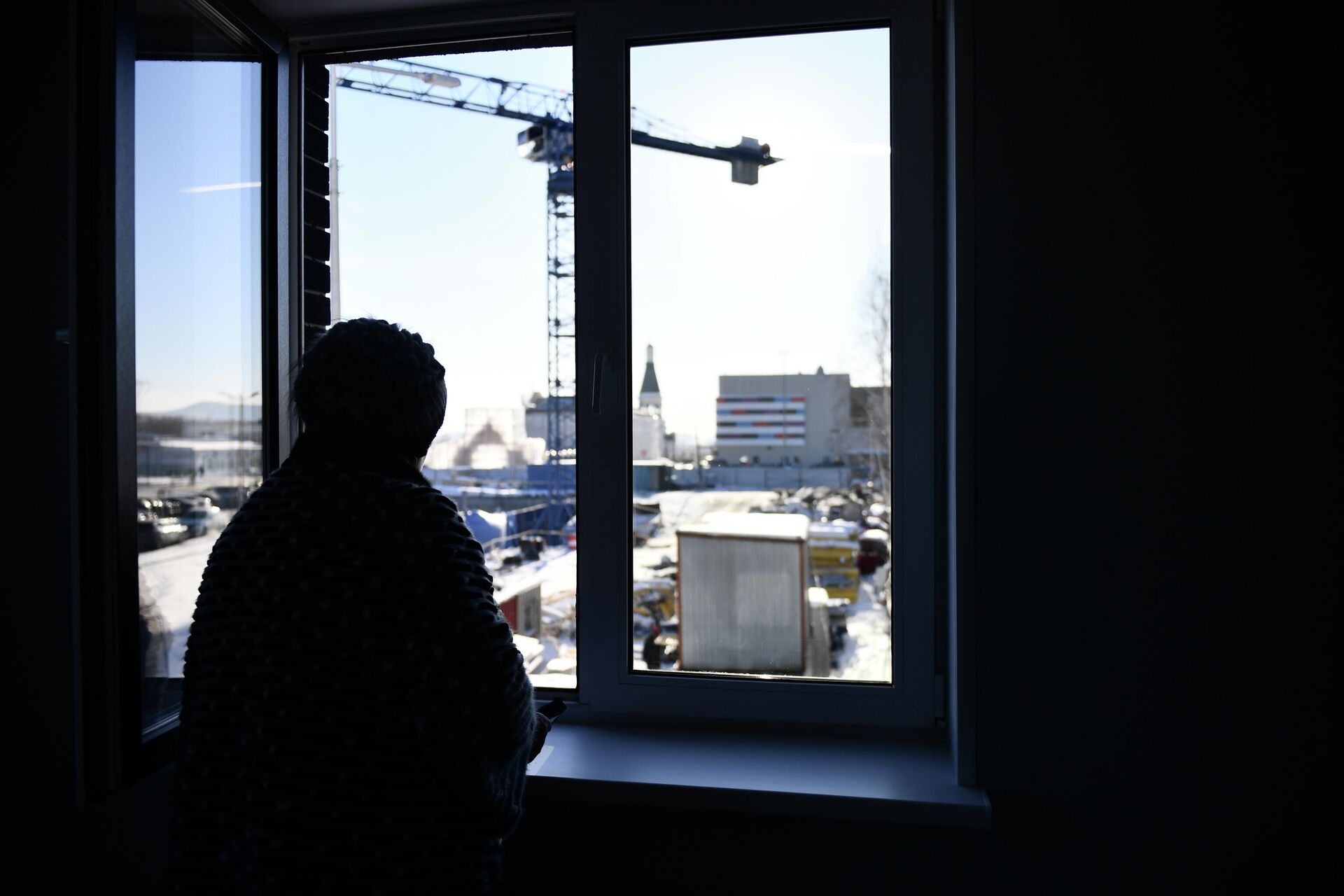 Женщина смотрит из окна своей квартиры в новом ЖК - РИА Новости, 1920, 16.03.2022