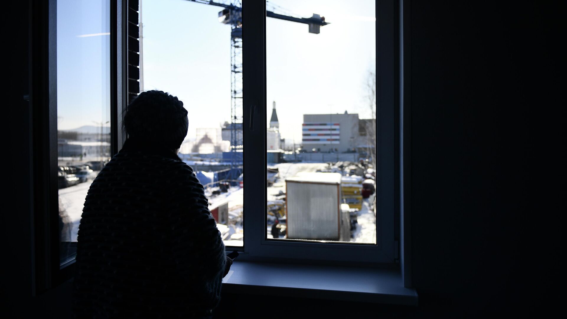 Женщина смотрит из окна своей квартиры в новом ЖК - РИА Новости, 1920, 03.03.2022