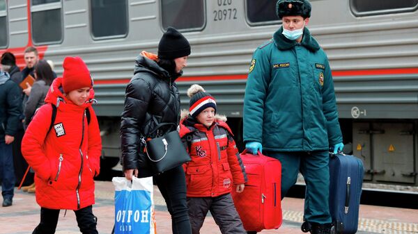 Сотрудник МЧС РФ помогает нести вещи эвакуированным жителям ДНР и ЛНР, прибывшим в Белгород