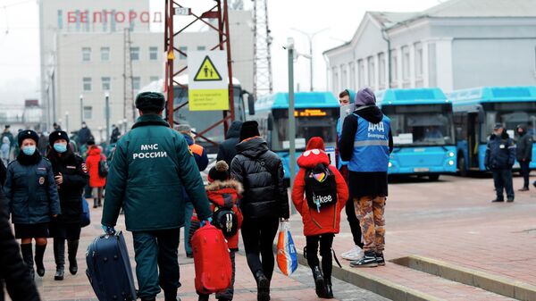 Сотрудник МЧС РФ помогает нести вещи эвакуированным жителям ДНР и ЛНР