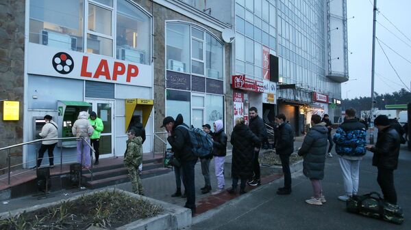 Люди стоят в очереди для того чтобы снять денежные средства в банкомате на одной из улиц в Киеве