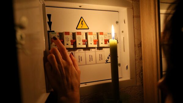 Девушка у электрического щитка в своей квартире во время тестового отключения электричества в Киеве