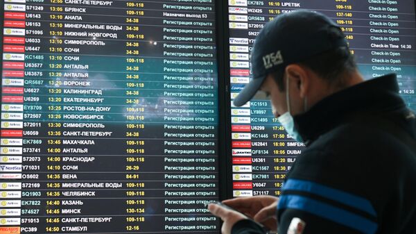 Мужчина возле электронного табло вылетов в аэропорту Домодедово в Москве