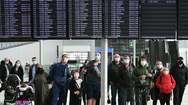 Пассажиры у информационного табло с рейсами в Международном аэропорту Стамбул, Турция