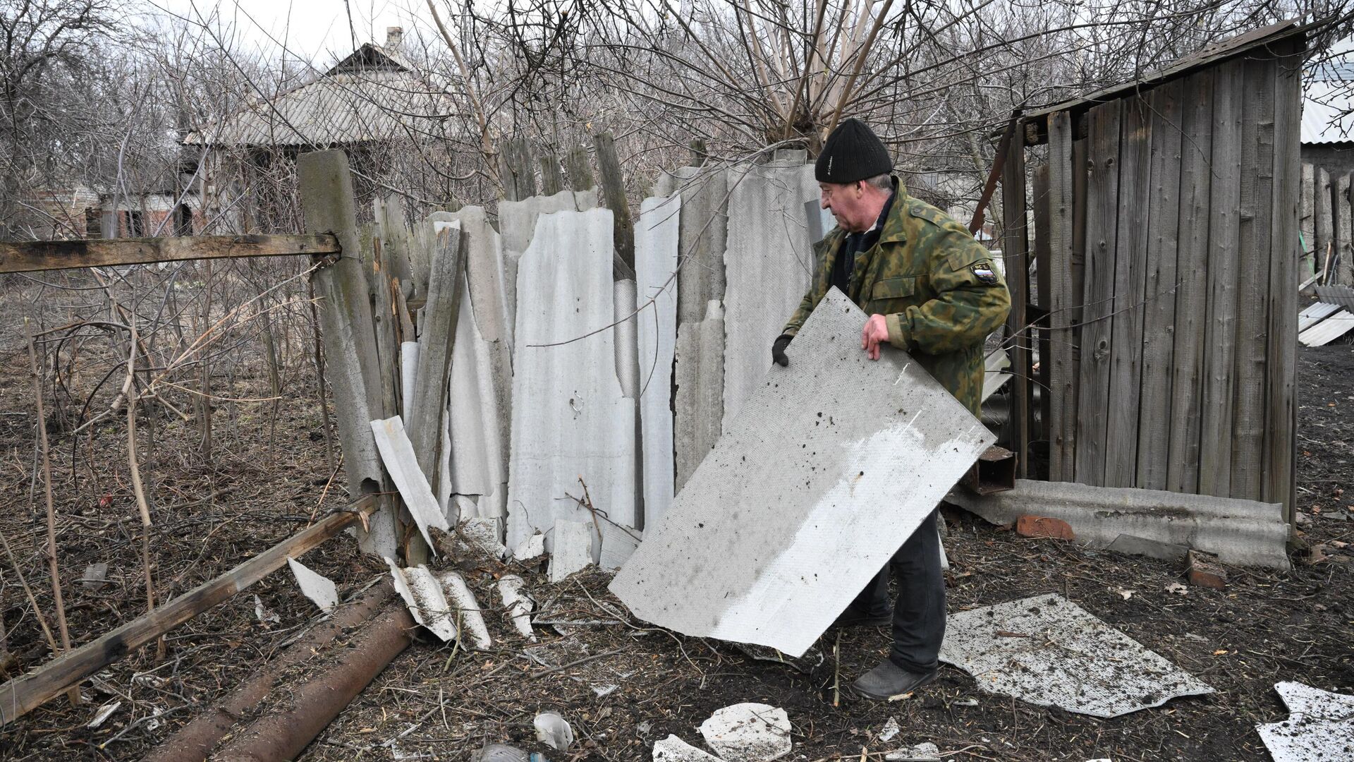 Мужчина расчищает территорию возле своего дома, разрушенную в результате обстрелов в поселке Финский в Горловке - РИА Новости, 1920, 21.04.2022