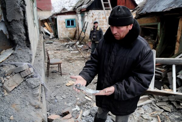 Мужчина демонстрирует осколок возле дома поврежденного в результате обстрела ВСУ поселка Зайцево в Горловке