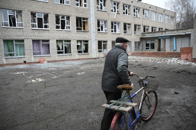 Мужчина у здания школы в Горловке, поврежденной в результате обстрела