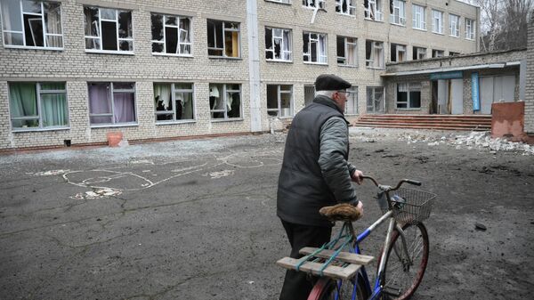 Мужчина у здания школы в Горловке, поврежденной в результате обстрела