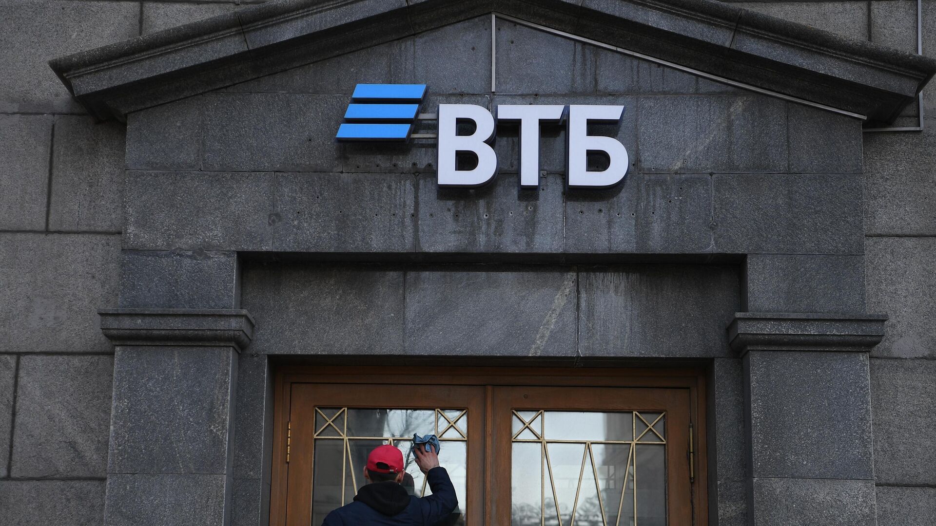 Сотрудник протирает стекла двери офиса ВТБ банка в Москве - РИА Новости, 1920, 02.03.2022