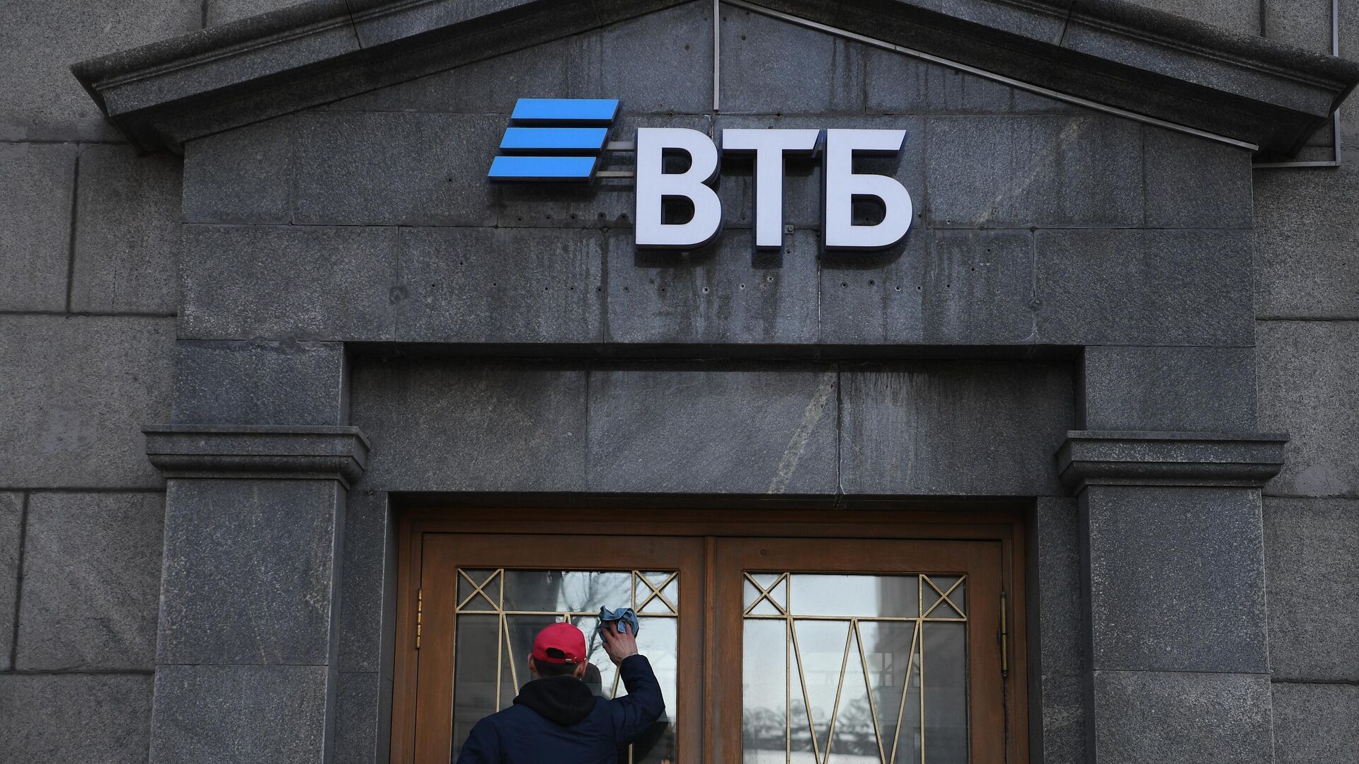 Сотрудник протирает стекла двери офиса ВТБ банка в Москве - РИА Новости, 1920, 03.03.2022