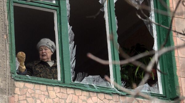 Женщина убирает осколки оконных стекол в здании школы в Горловке, поврежденном в результате обстрела