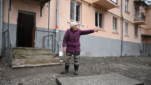 Жительница во дворе жилого дома, подвергшегося обстрелу в Киевском районе Донецка