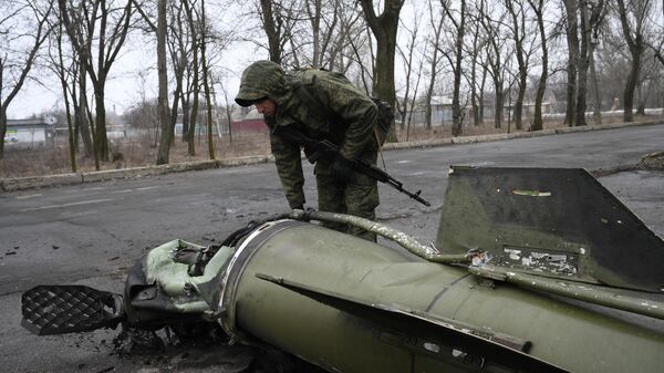 Военнослужащий осматривает осколок ракеты в Донецке