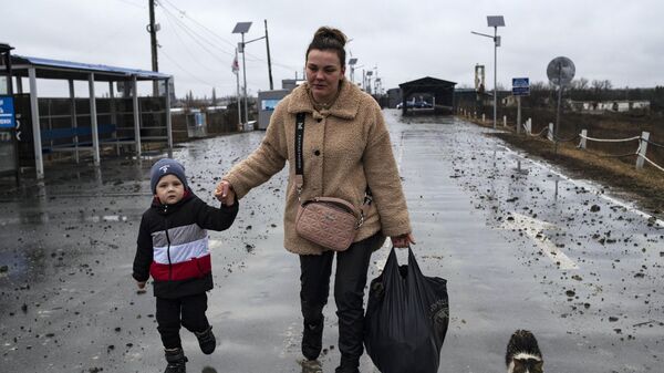 Женщина с ребенком идут по дороге у Станицы Луганская, которая перешла под контроль ЛНР
